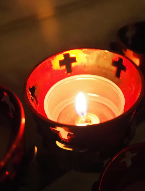 A lit red votive candle glowing in the dark