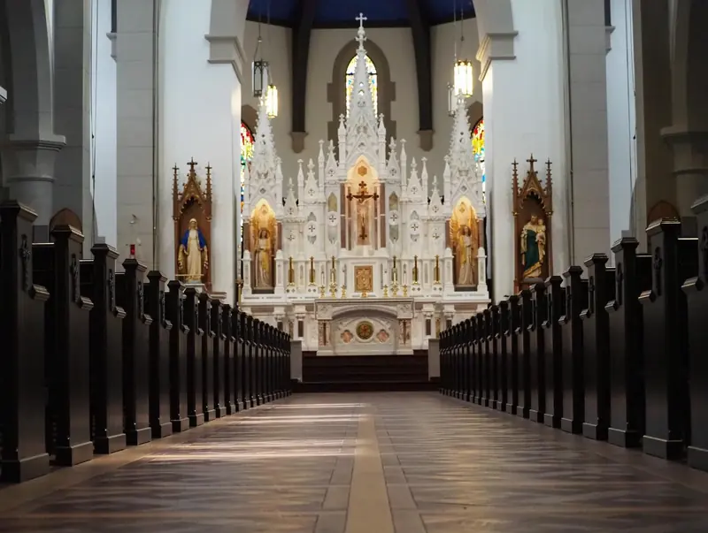 Symmetrical view down the aisle of a white gothic chapel