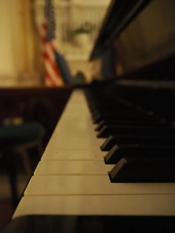 Low angle along the keys of a grand piano in warm light