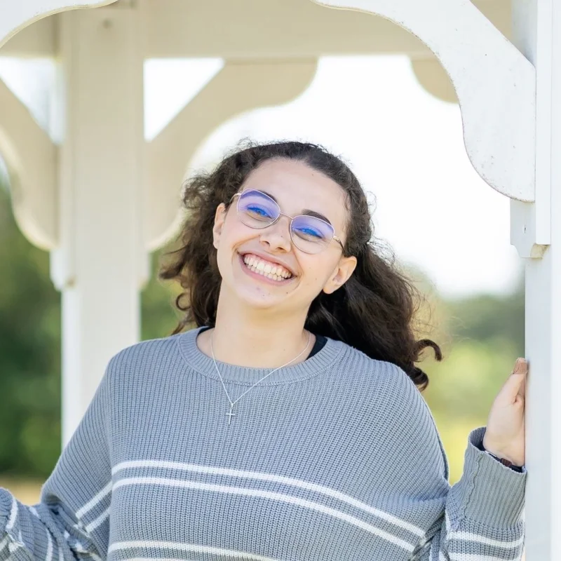 Monica in a striped sweater smiling in a white gazebo