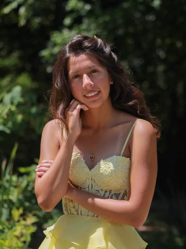 Quinceañera in a yellow lace dress smiling with her hand to her cheek