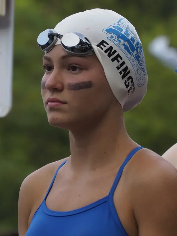 Swimmer with eye black and a team cap staring ahead before her race