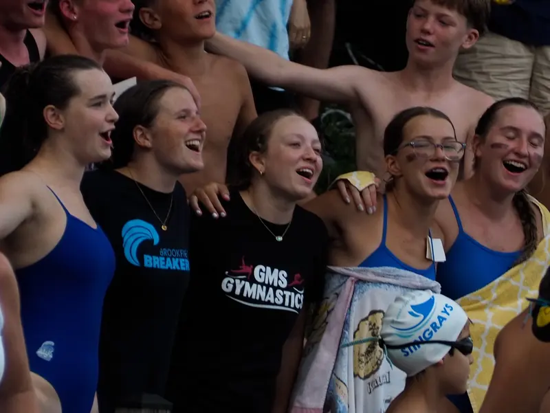 Swim team cheering loudly from the side of the pool
