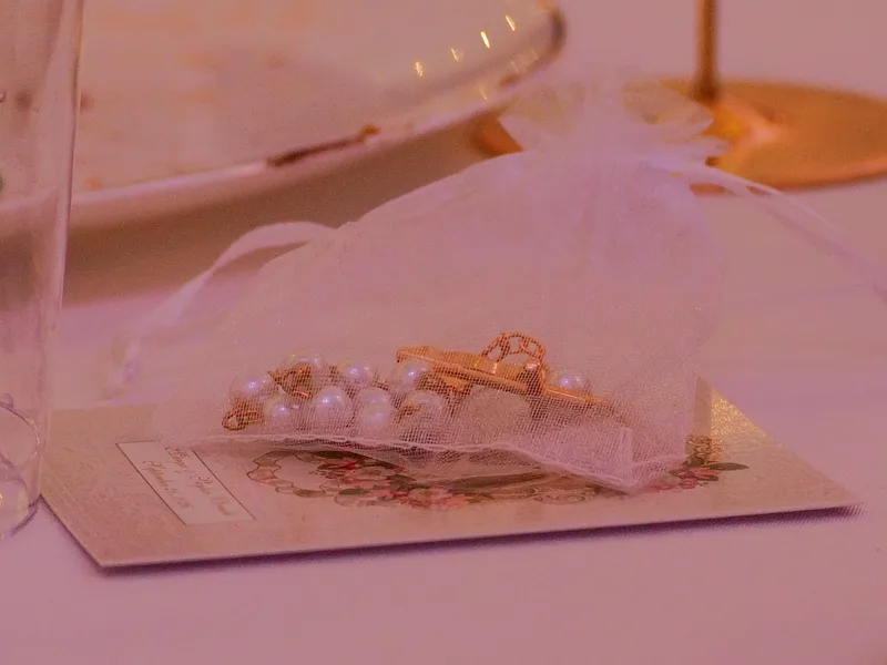 Pearl rosary favor in a sheer organza bag on a place card at a wedding reception table